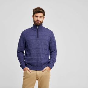 Kuna Watson Sweater - model wearing blue sweater with wide spaced horizontal ribbing and zippered collar on a neutral background