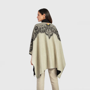Kuna Wendy Poncho - model wearing white poncho with black lining and floral detail on a neutral background