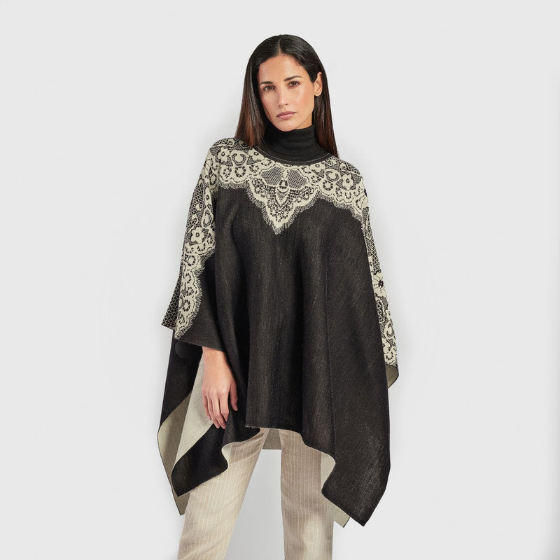 Kuna Wendy Poncho - model wearing black poncho with white lining and floral detail on a neutral background
