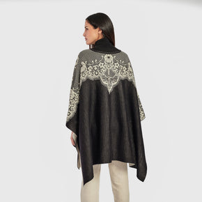 Kuna Wendy Poncho - model wearing black poncho with white lining and floral detail on a neutral background