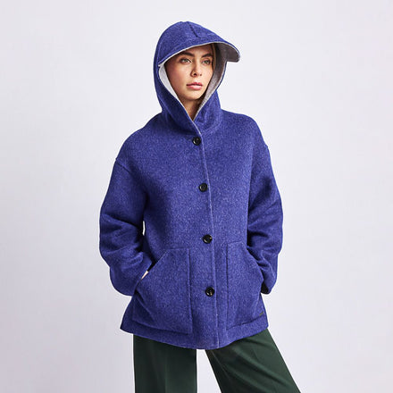 Kuna Whoopi Coat - model wearing blue hooded coat with grey lining, large pockets, and black buttons on a neutral background