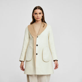 Kuna Willianne Coat - model wearing white coat with tan lining and black buttons on a neutral background