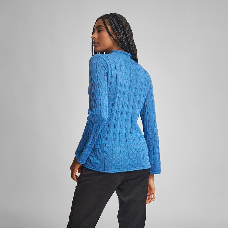 Kuna Willow Sweater - model wearing blue mock turtle neck sweater with cabling on a neutral background