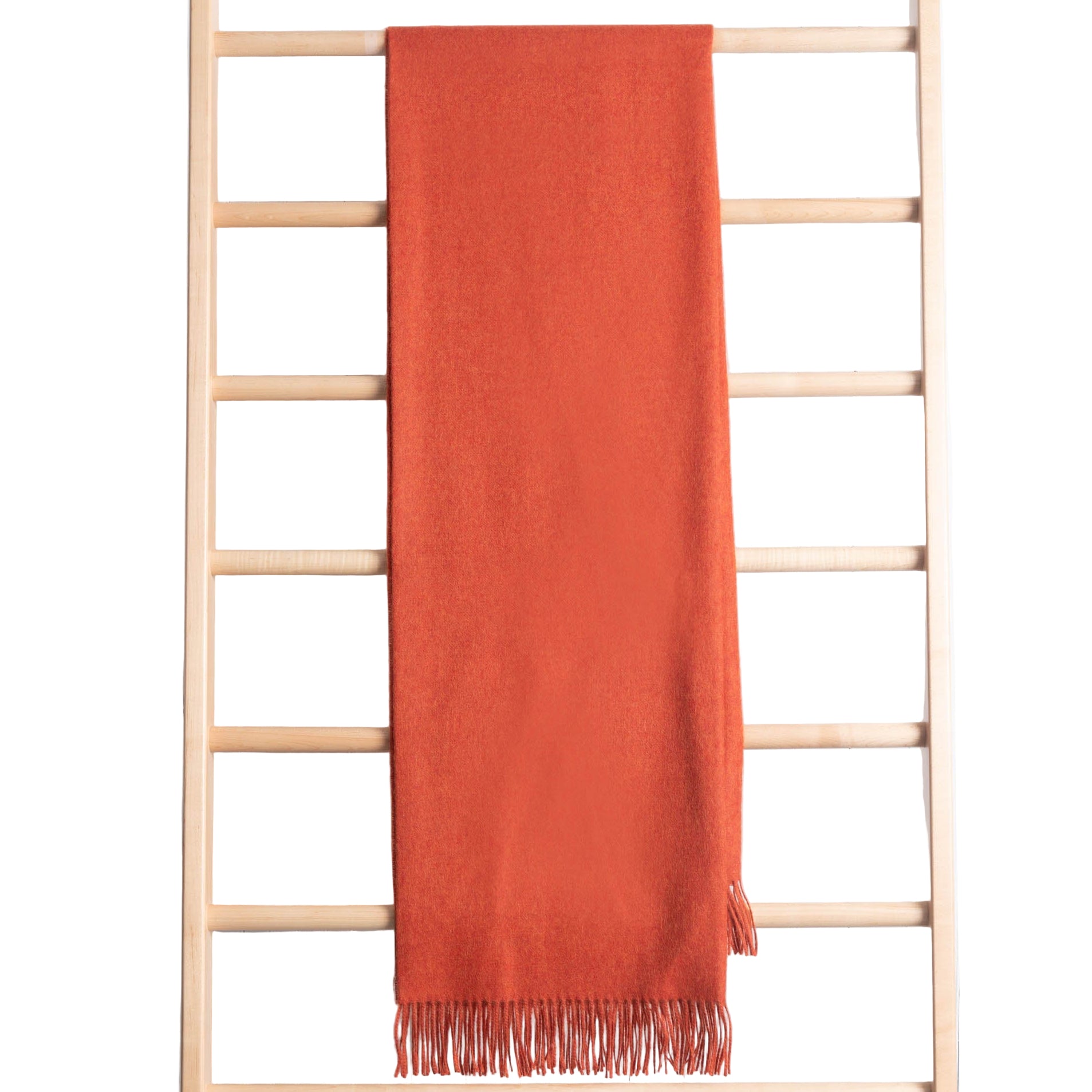 Orange throw draped over a wooden ladder against a light wooden panel background