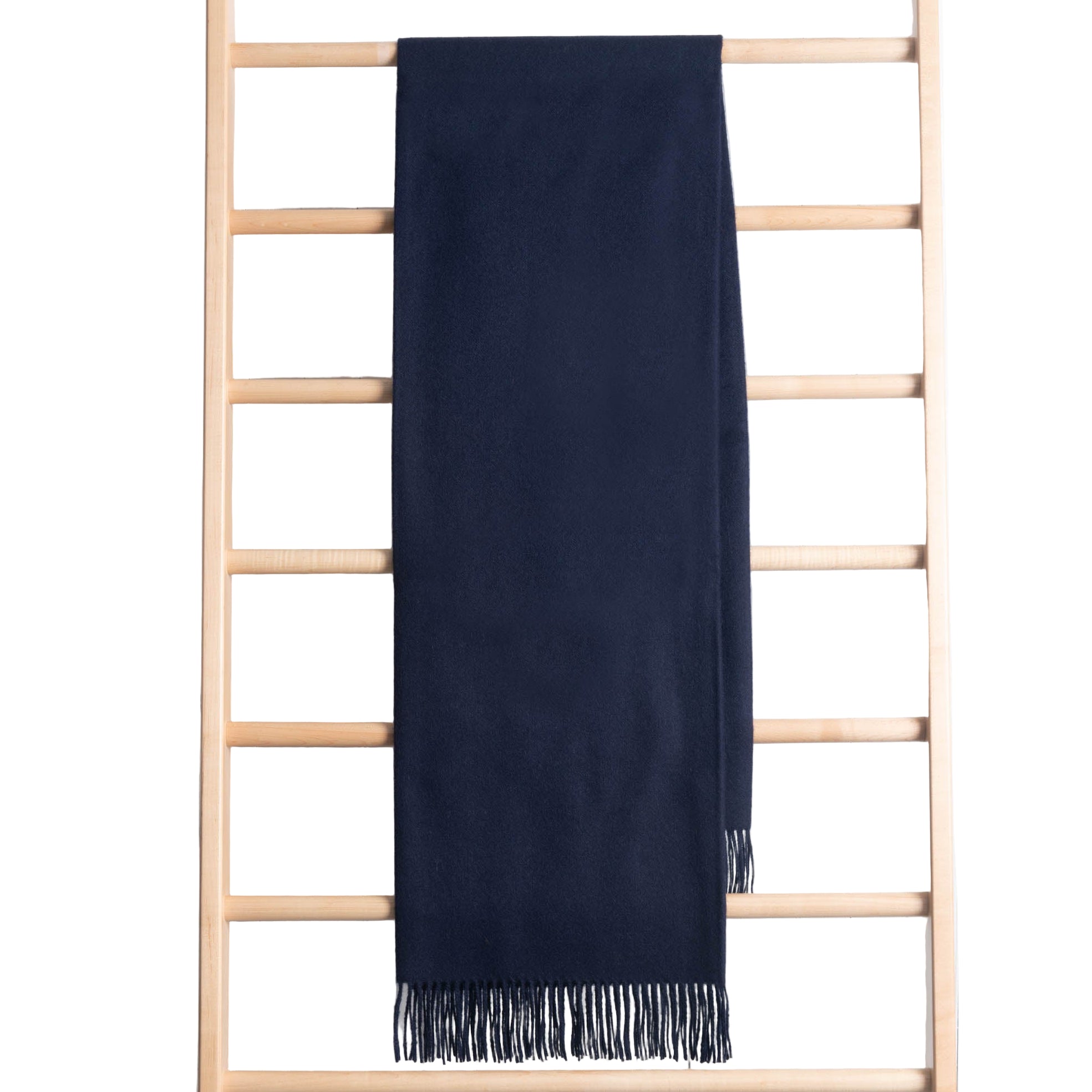 Navy blue throw with fringes on a wooden ladder against a white background
