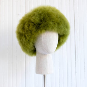 Premium Baby Alpaca Fur Hat. A green Premium Baby Alpaca Fur Hat on a mannequin head against a white paneled background.
