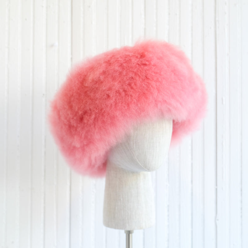 Premium Baby Alpaca Fur Hat. A pink Premium Baby Alpaca Fur Hat on a mannequin head against a white paneled background.