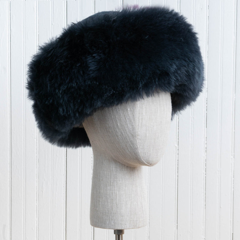 Premium Baby Alpaca Fur Hat. A bluish charcoal Premium Baby Alpaca Fur Hat on a mannequin head against a white paneled background.