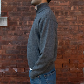 Men's Heavyweight Full-Zip 100% Baby Alpaca Wool Jacket, a man in a steel gray alpaca jacket stand to the side in front of a brick wall.