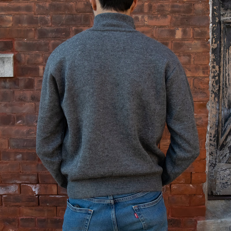 Men's Heavyweight Full-Zip 100% Baby Alpaca Wool Jacket, a man in a steel grey baby alpaca jacket faces away from the camera in front of a brick wall.
