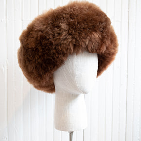 Premium Baby Alpaca Fur Hat. A brown Premium Baby Alpaca Fur Hat on a mannequin head against a white paneled background.
