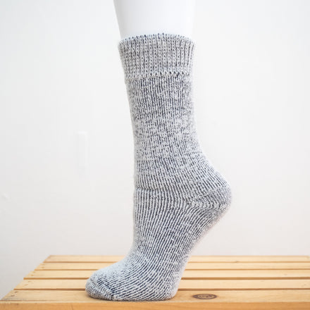 Andinista Alpaca Hiking Socks, a picture of a foot wearing a pair of silver alpaca socks on a wooden crate. 