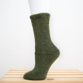 Andinista Alpaca Hiking Socks, a picture of a foot wearing a pair of green alpaca hiking socks on a wooden crate. 