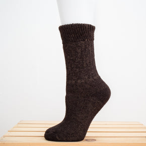 Andinista Alpaca Hiking Socks, a picture of a foot wearing a pair of brown alpaca hiking socks on a wooden crate. 