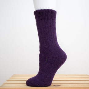 Andinista Alpaca Hiking Socks, a picture of a foot wearing a pair of purple alpaca hiking socks on a wooden crate. 