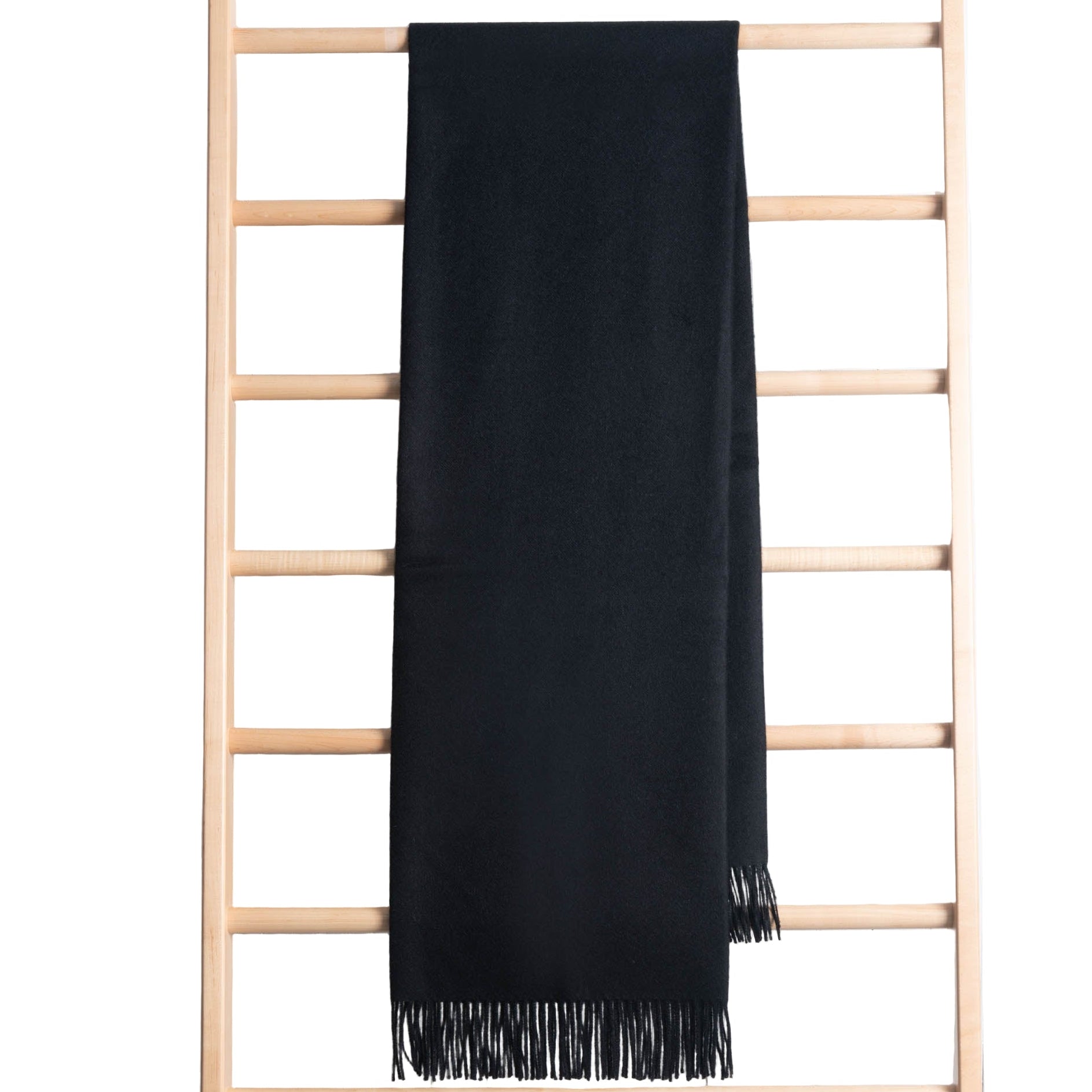 Black throw draped over a wooden ladder against a white wooden panel background
