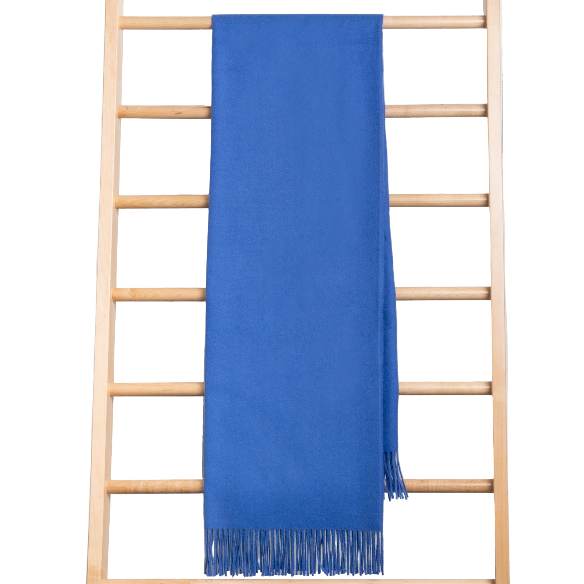 Blue throw with fringes draped over a wooden ladder on a white background