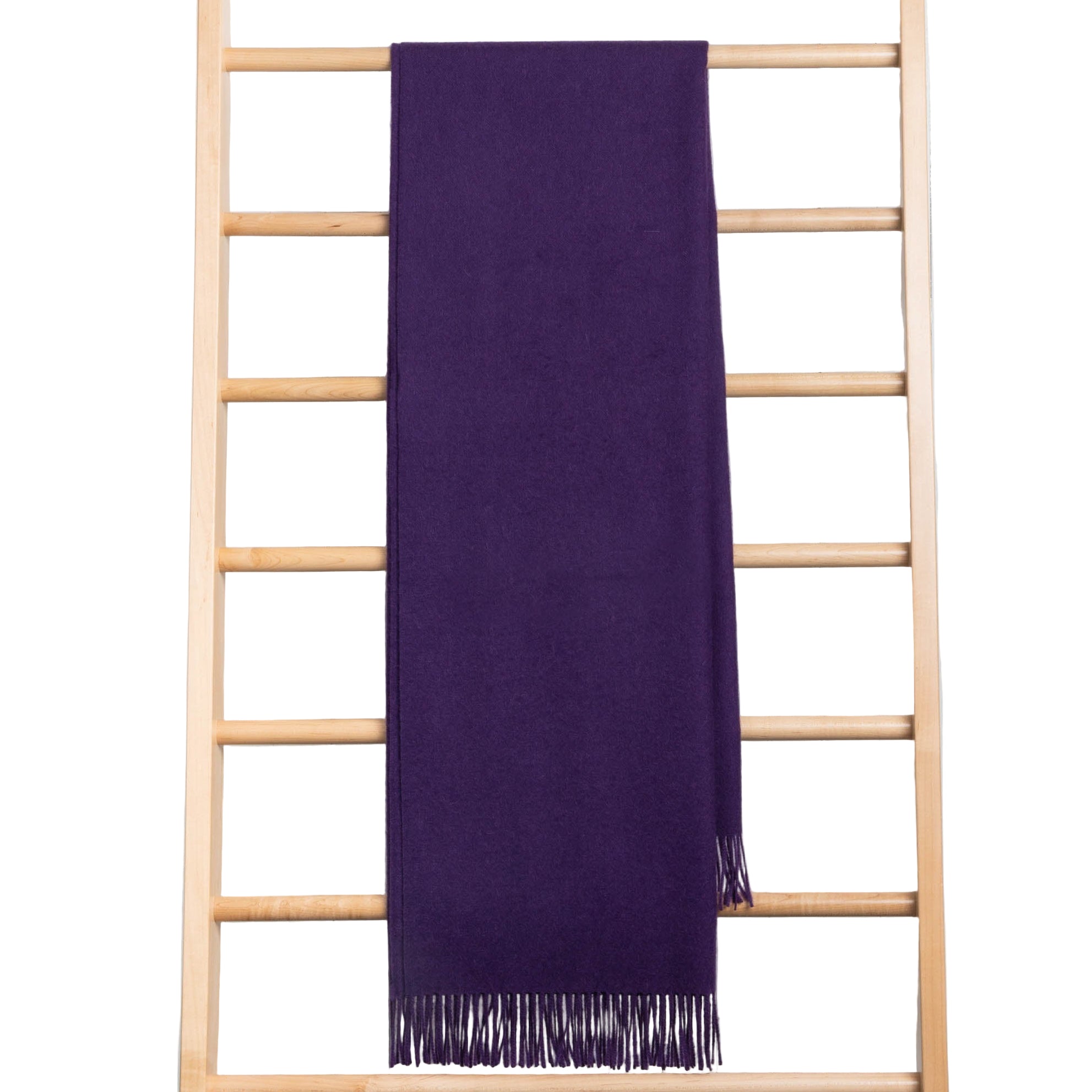 Purple throw with fringe on a wooden ladder against a white background