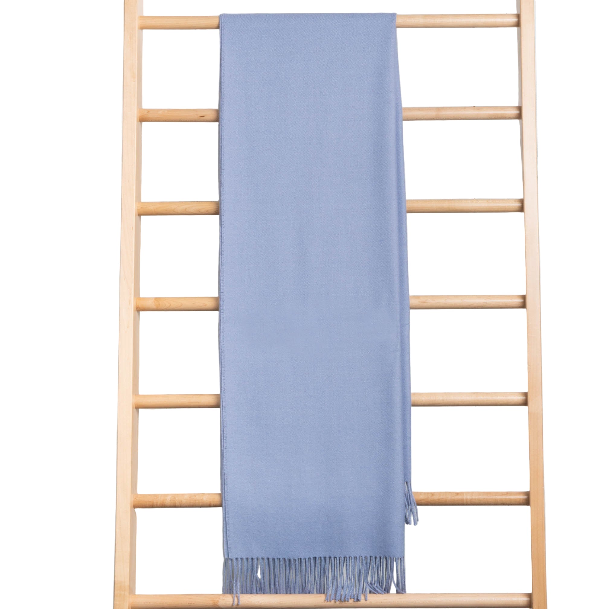Blue throw draped over a wooden ladder against a wooden panel background