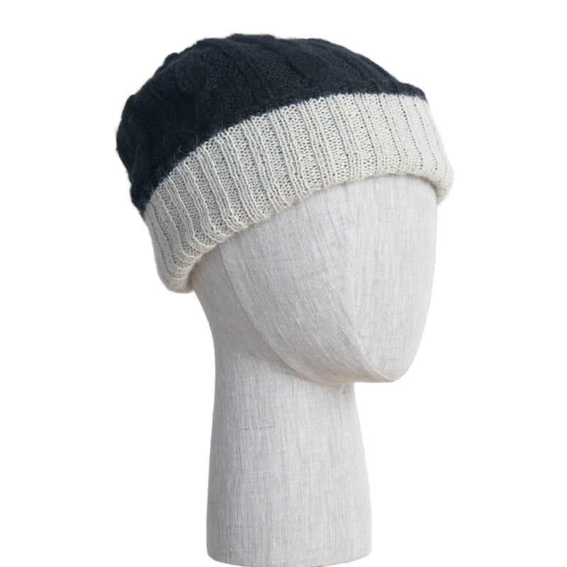 Black and white knit beanie on a mannequin head against a white wooden panel background