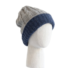 Two-toned knit beanie on a mannequin head against a white wooden panel background
