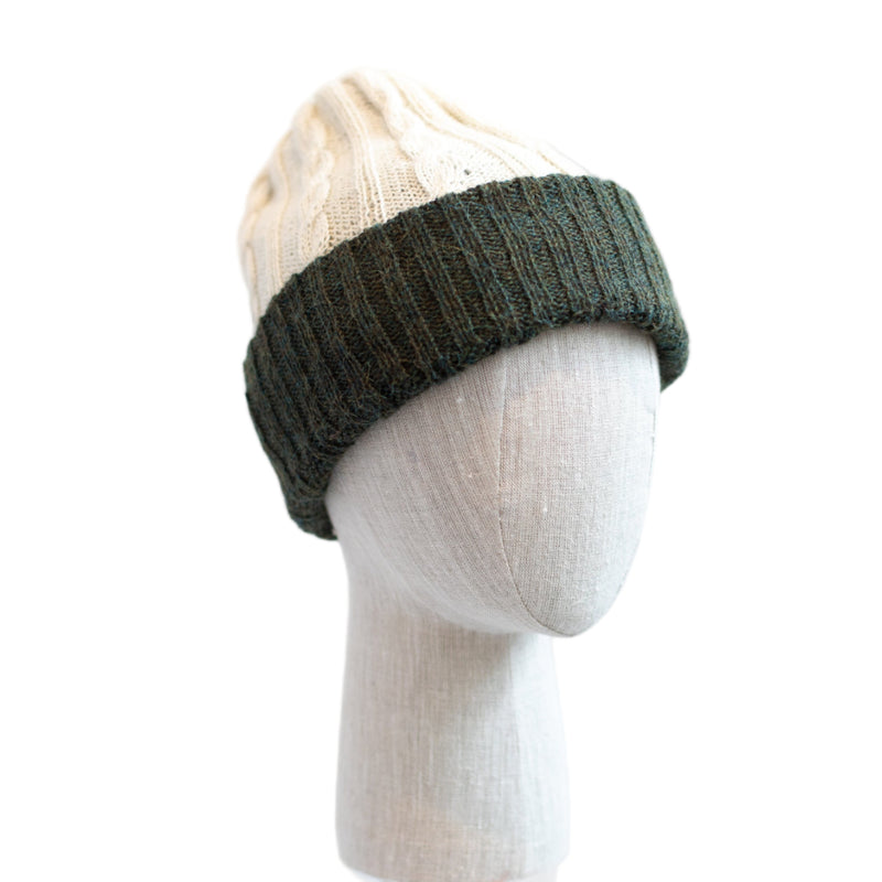 Green knit beanie on a mannequin head against a white background