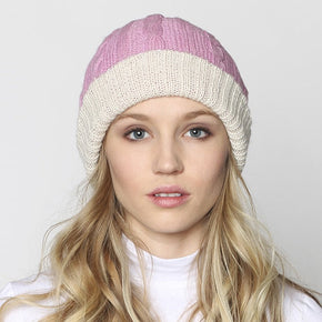 Woman wearing a two-tone pink and white beanie on a plain background