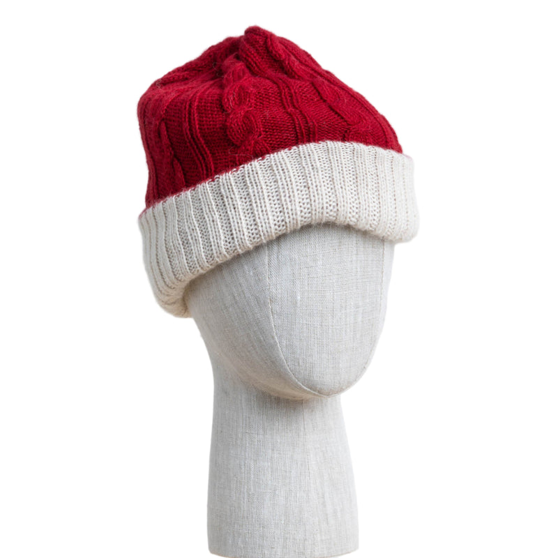 Red and white knitted beanie on a mannequin head against a light wooden panel background