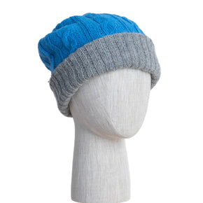 Two-toned blue and gray knit beanie on a mannequin head against a white wooden panel background.