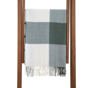 A baby alpaca shawl with a buffalo plaid pattern in gray and white colors, displayed on a wooden hanger.