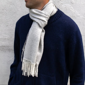 Person wearing a navy sweater and light gray scarf against a light gray background