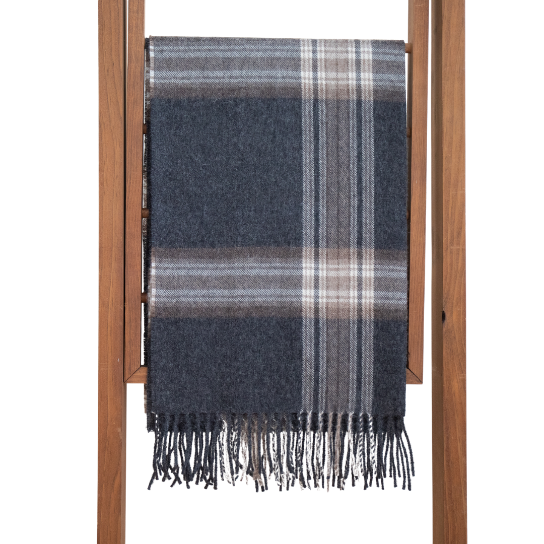 A multicolored plaid baby alpaca shawl displayed on a wooden hanger, with a variety of colors including blue, red, orange, and purple.
