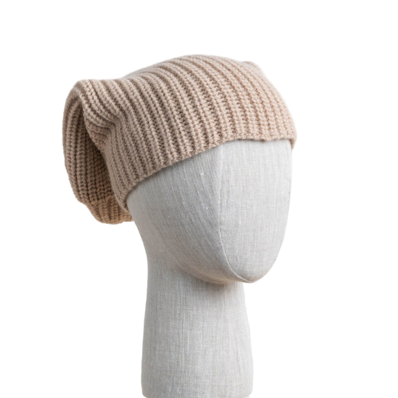 An oversized beige knit alpaca hat displayed on a mannequin head against a white background.
