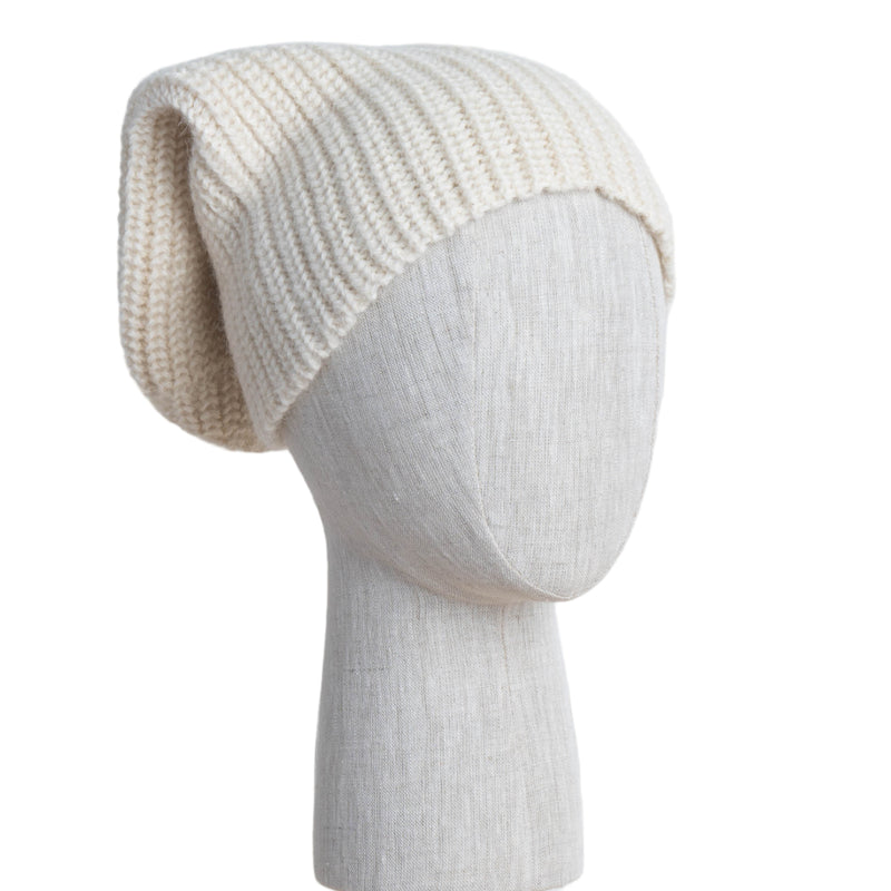 Knitted cream beanie on a mannequin head against a white wooden panel background