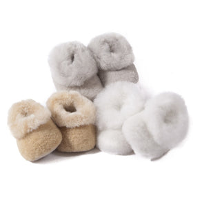 A collection of alpaca baby booties with merino fleece lining, displayed in beige, gray, and white colors.