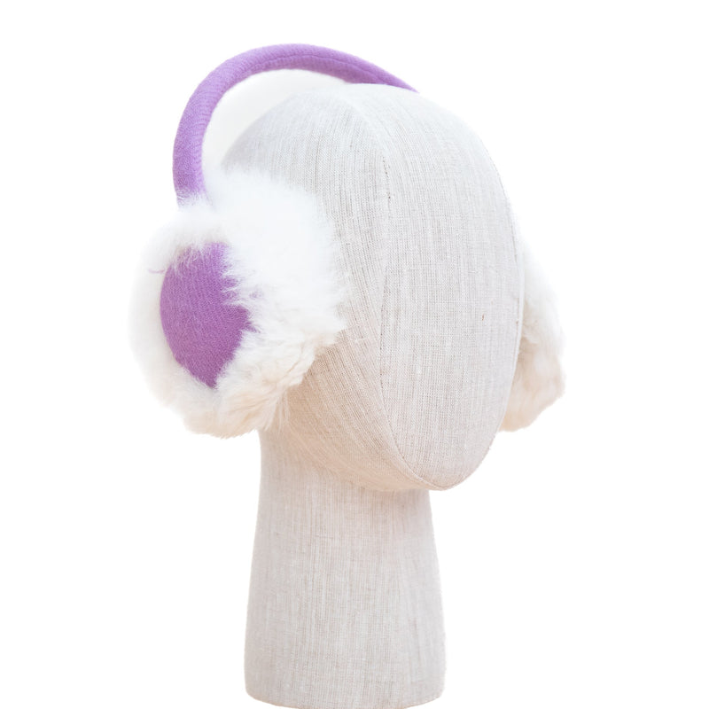 purple ear muffs on a mannequin head against a white background