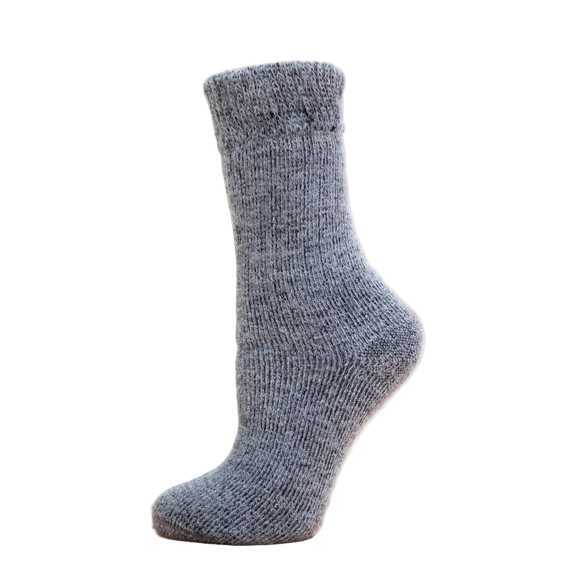 Andinista Alpaca Hiking Socks, a picture of a foot wearing a pair of grey alpaca socks on a wooden crate. 