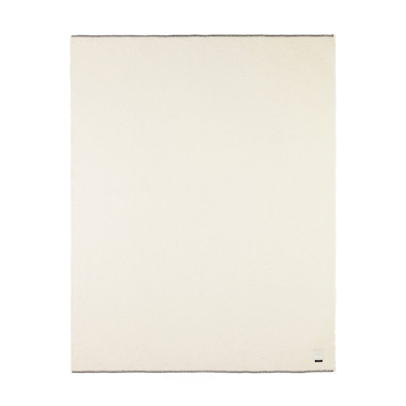 A monochromatic ivory-colored blanket with a rolled hem and blanket stitching.