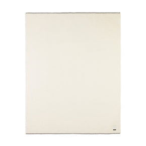 A monochromatic ivory-colored blanket with a rolled hem and blanket stitching.