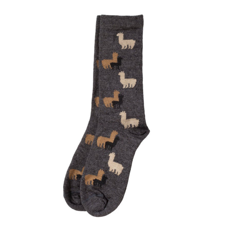 A pair of children's socks with a natural herd pattern of alpacas on a charcoal background, displayed against a white wooden backdrop.