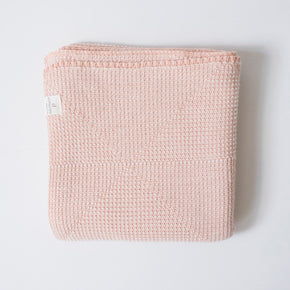 A folded pink baby blanket with a textured pattern, displayed on a plain background.