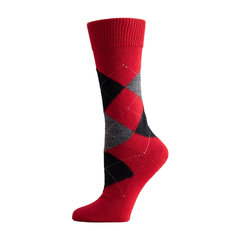Red and black argyle sock on a wooden surface with a white background