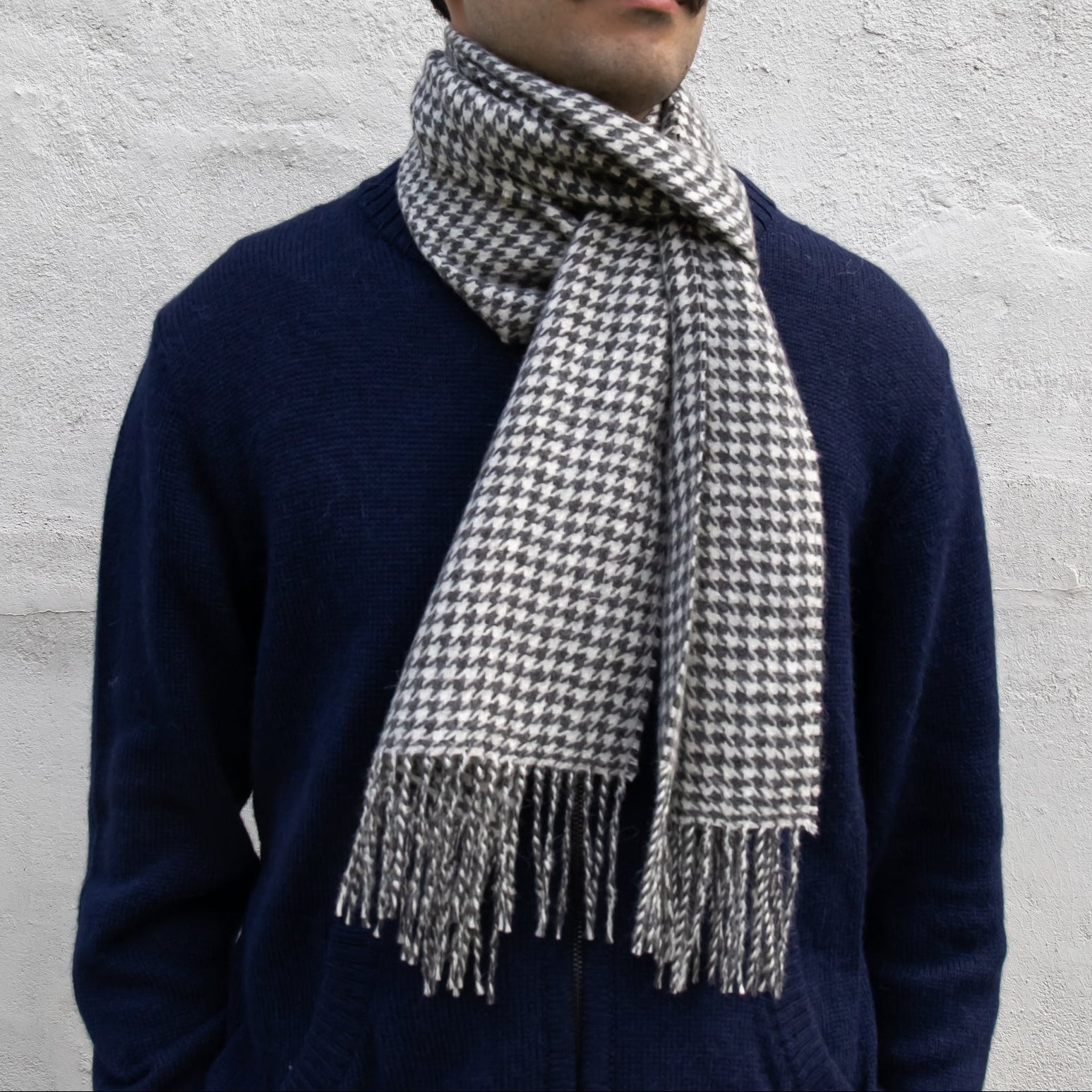 Man wearing a houndstooth patterned scarf against a light gray background