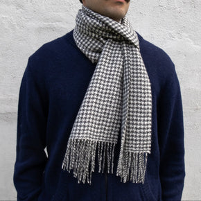 Man wearing a houndstooth patterned scarf against a light gray background