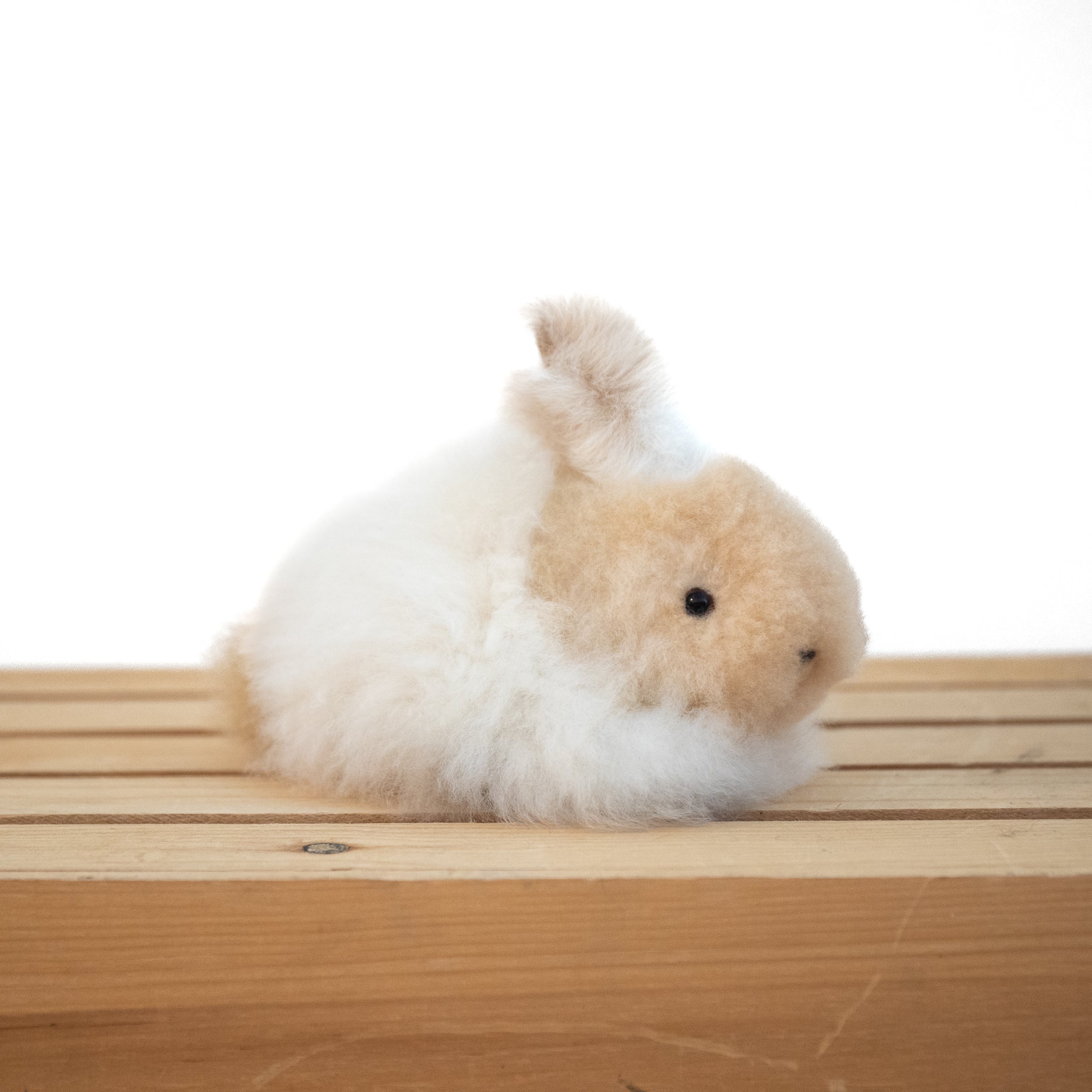Plush alpaca fur toy bunny on a neutral background