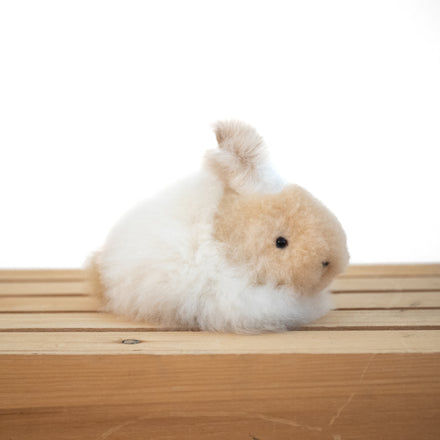 Plush alpaca fur toy bunny on a neutral background