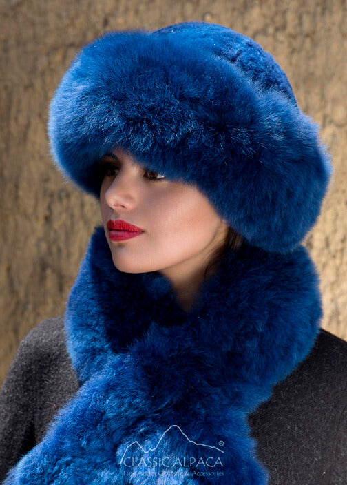Premium Baby Alpaca Fur Hat. A woman wearing a blue alpaca fur hat and matching blue stole scarf in front of a natural background. 