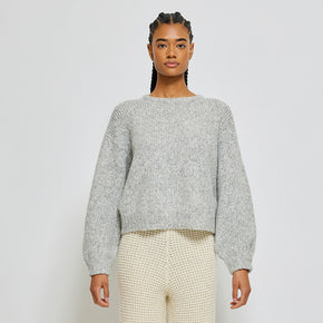 Person wearing light grey knit sweater on white background