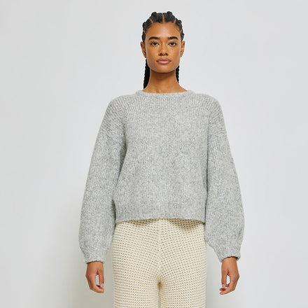 Person wearing light grey knit sweater on white background