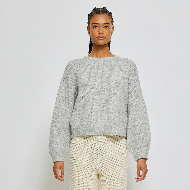Person wearing light grey knit sweater on white background
